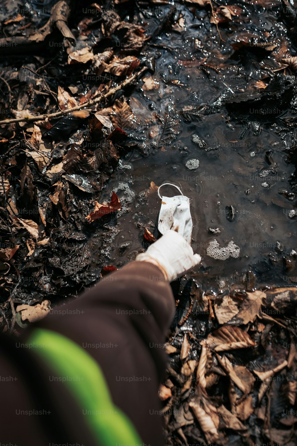 a person holding something in their hand near a puddle of water