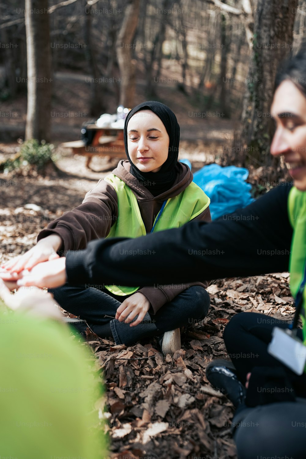 two women sitting on the ground in the woods