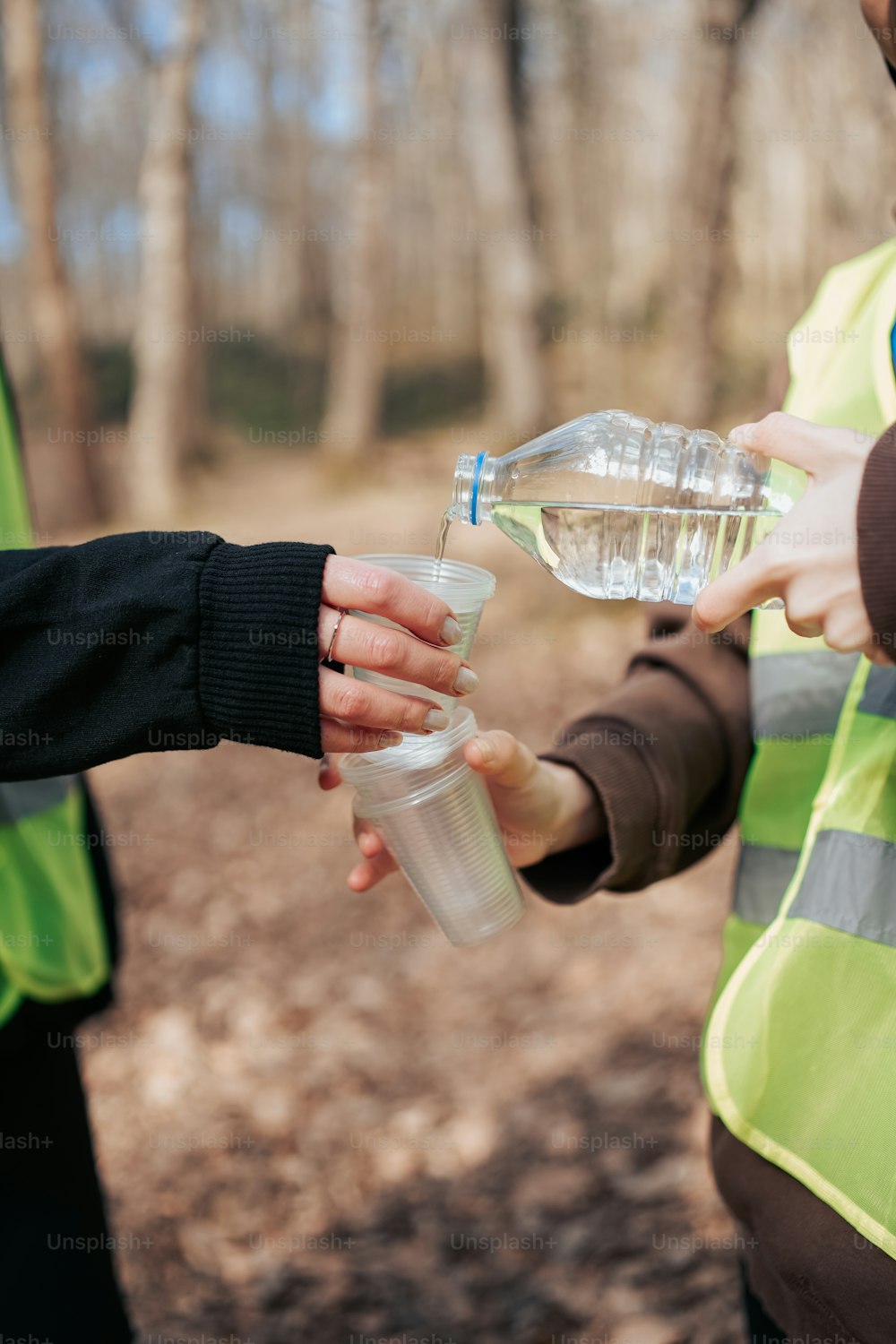 Zwei Personen in Warnwesten halten Wasserflaschen in der Hand