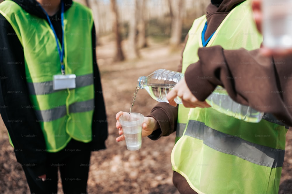 a person in a safety vest pouring water into a cup