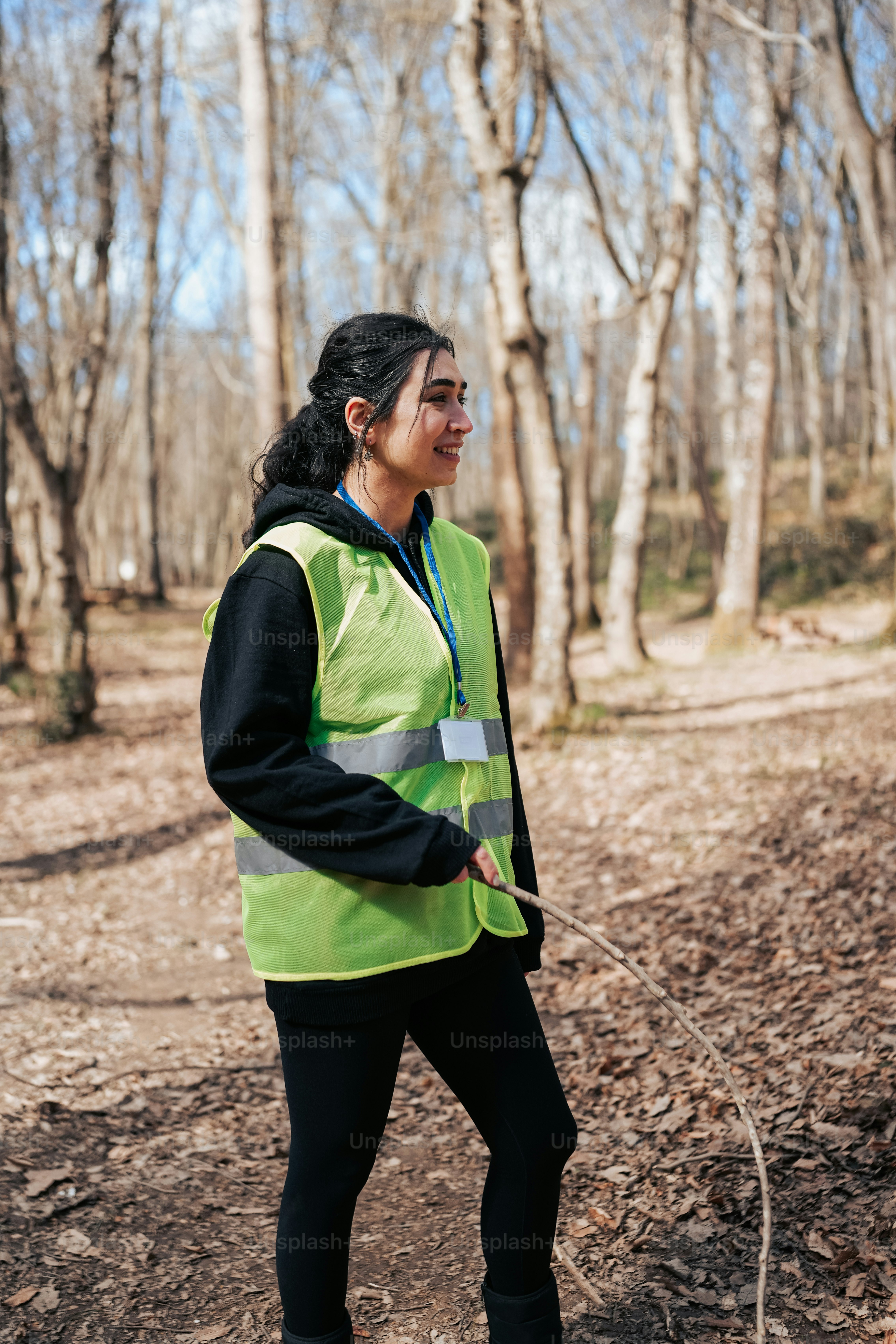 a woman in a safety vest is walking through the woods