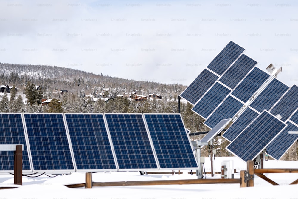 Un gruppo di pannelli solari seduti sopra il terreno innevato