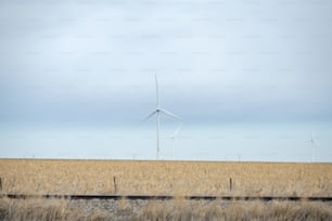 a field with a few windmills in the distance