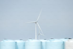 Una turbina eólica junto a una fila de tanques azules