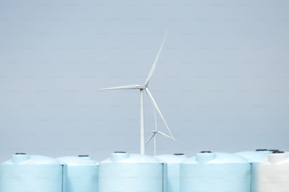 a wind turbine next to a row of blue tanks