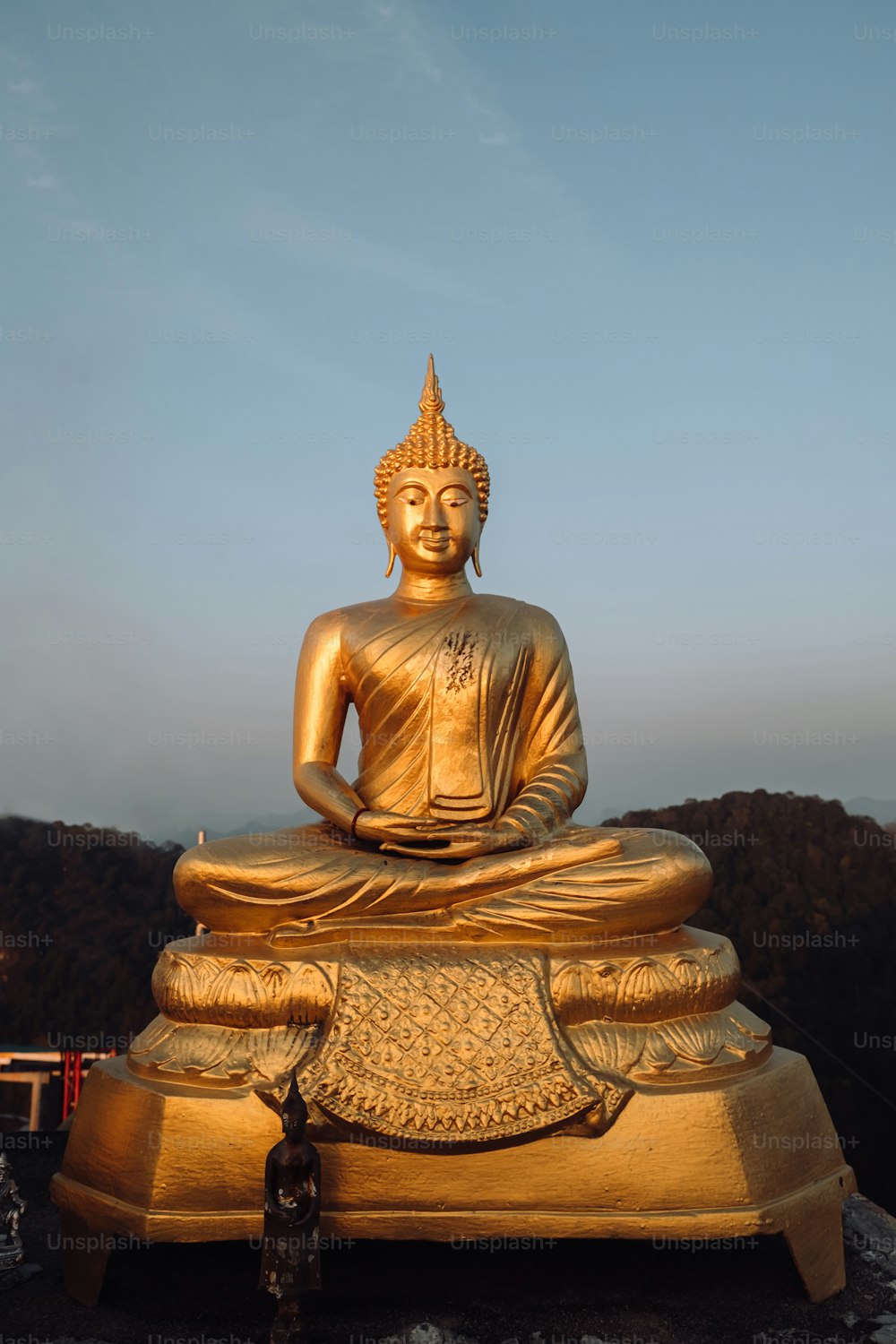 uma estátua dourada de Buda sentada no topo de uma rocha