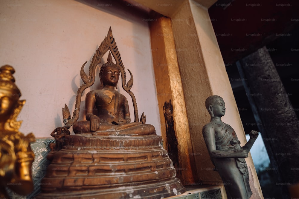 Una estatua de un Buda sentado junto a una estatua de una persona