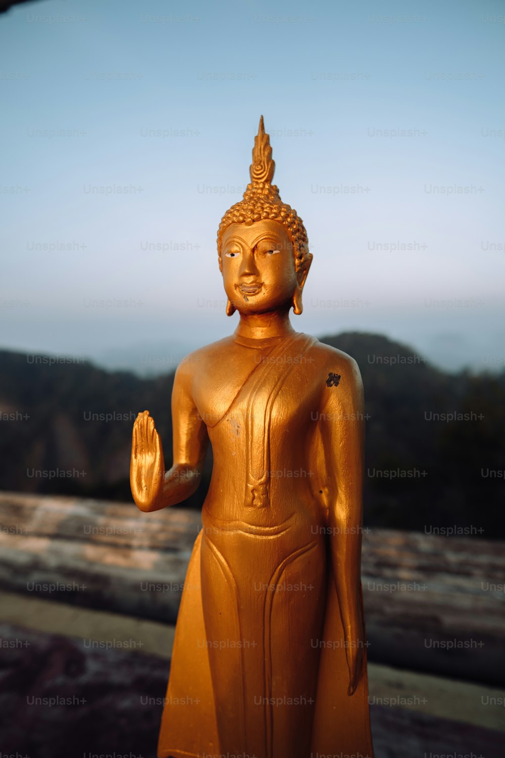 uma estátua dourada de buddha com uma montanha no fundo