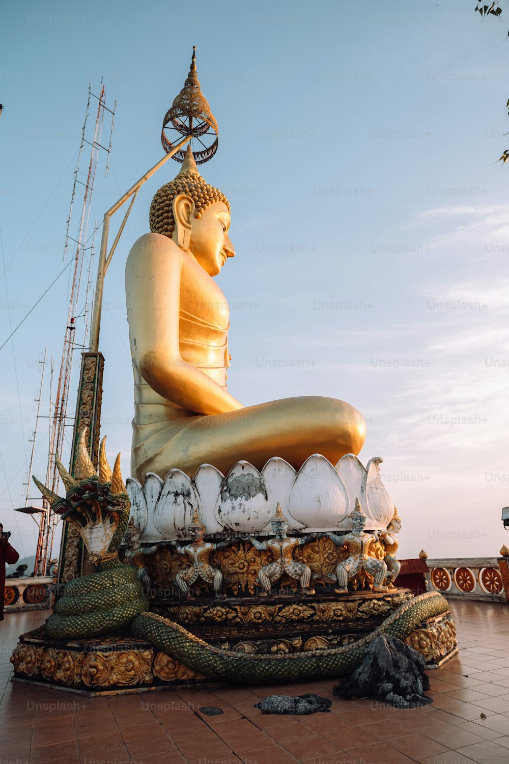 Una grande statua dorata di Buddha seduta in cima a un pavimento piastrellato