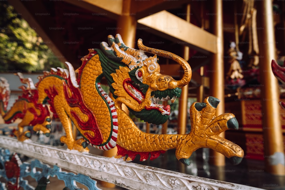 a row of dragon statues sitting on top of a wooden fence