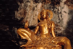 Una estatua dorada de Buda sentada en una cueva