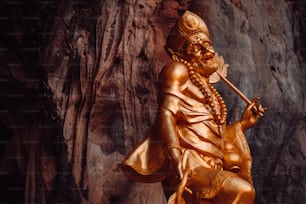 une statue dorée d’un homme avec une canne