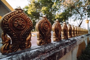 a row of carved wooden railings with trees in the background
