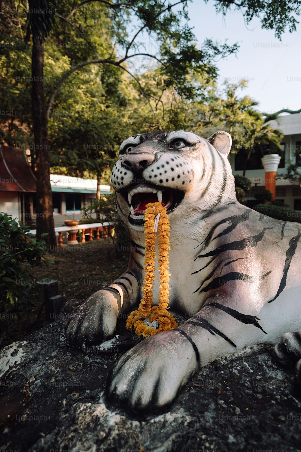 Una statua di una tigre con un fiore in bocca