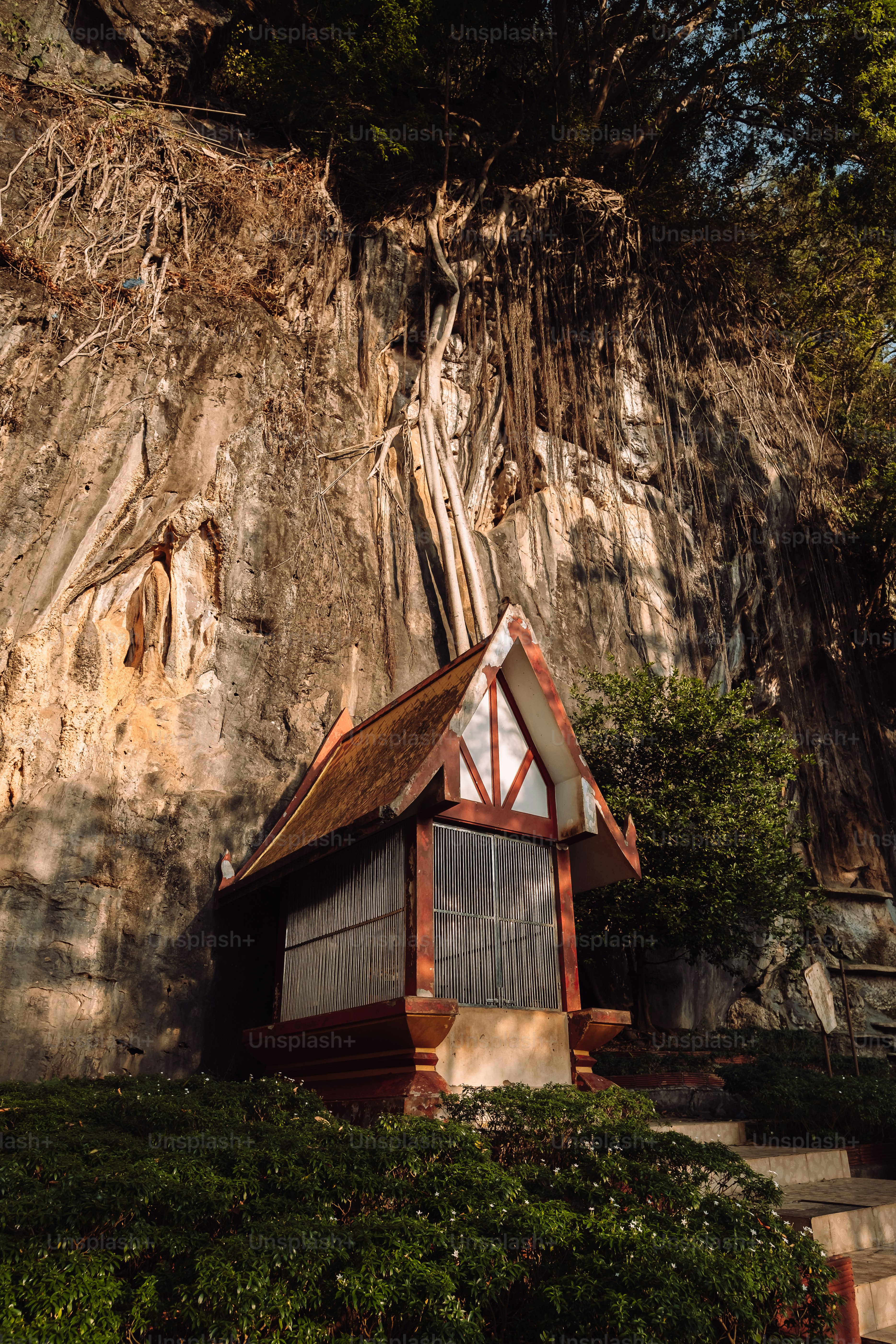 a small building in front of a large rock face