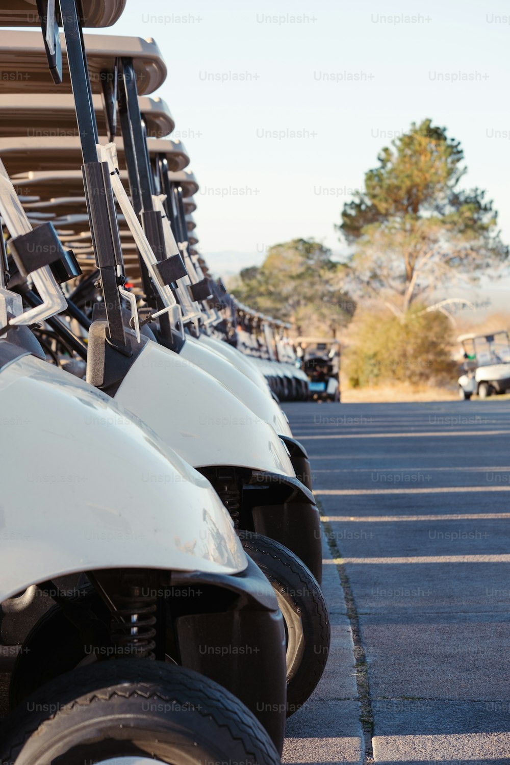 a row of white golf carts parked in a parking lot