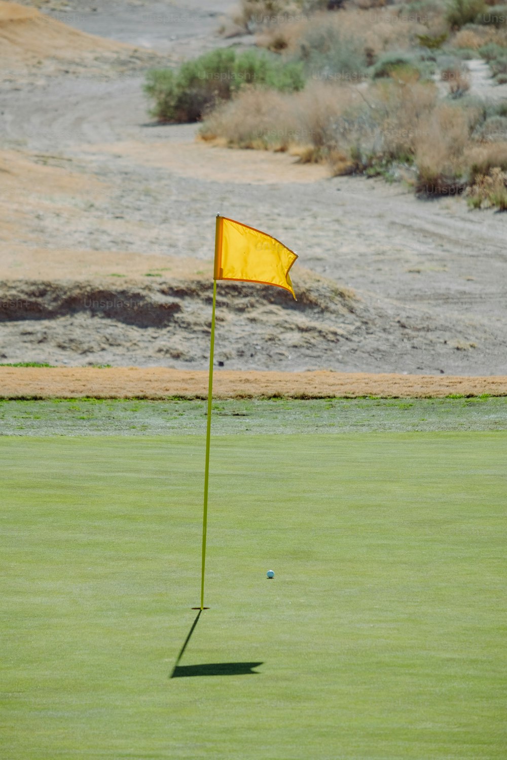 a yellow flag sticking out of the green of a golf course
