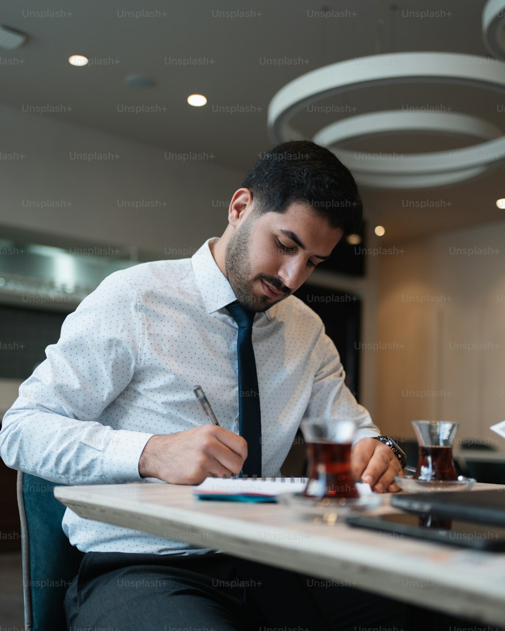Un homme assis à une table �écrivant sur un morceau de papier
