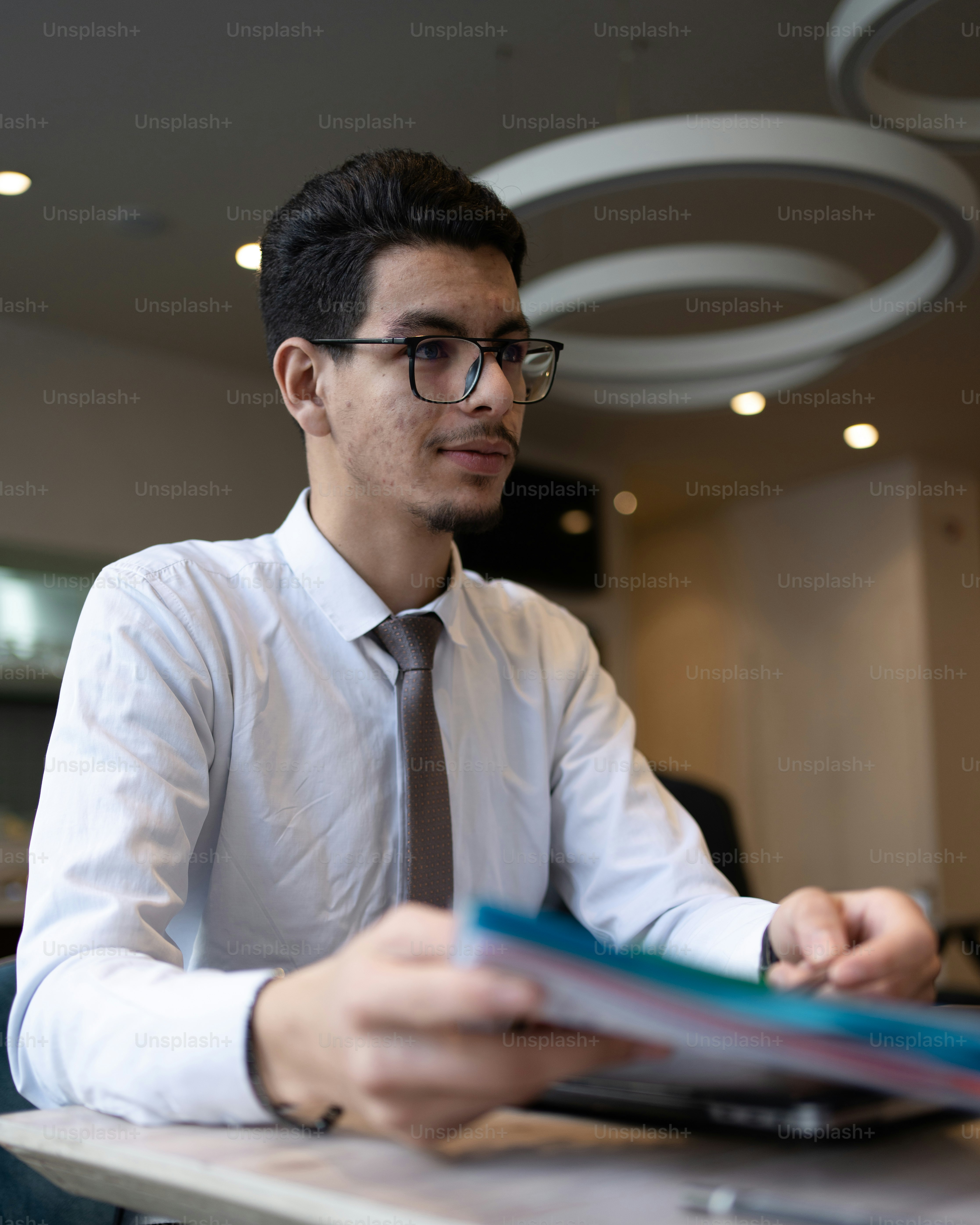 a man wearing glasses and a tie sitting at a table