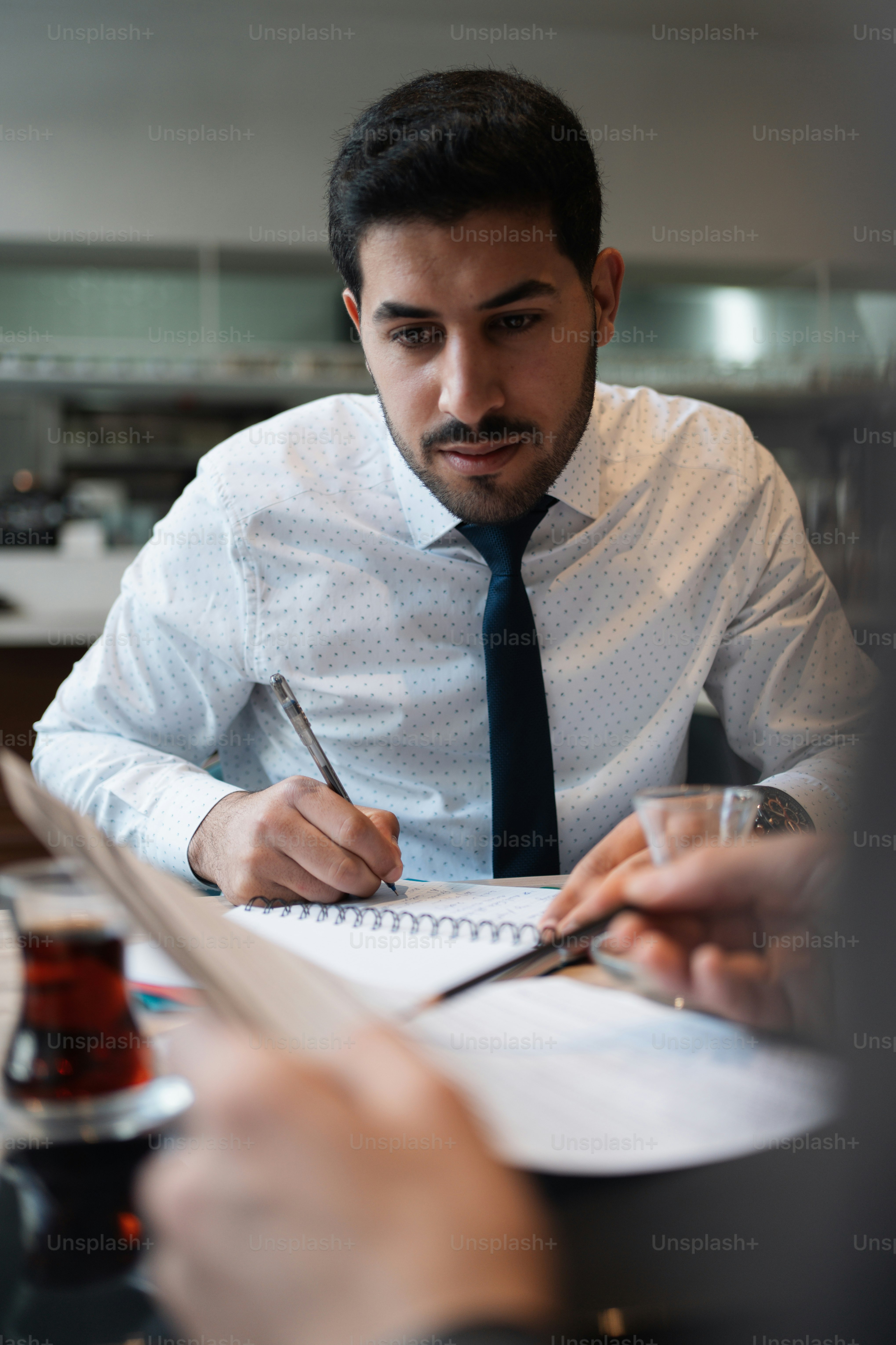 Un homme assis à une table écrivant sur un morceau de papier