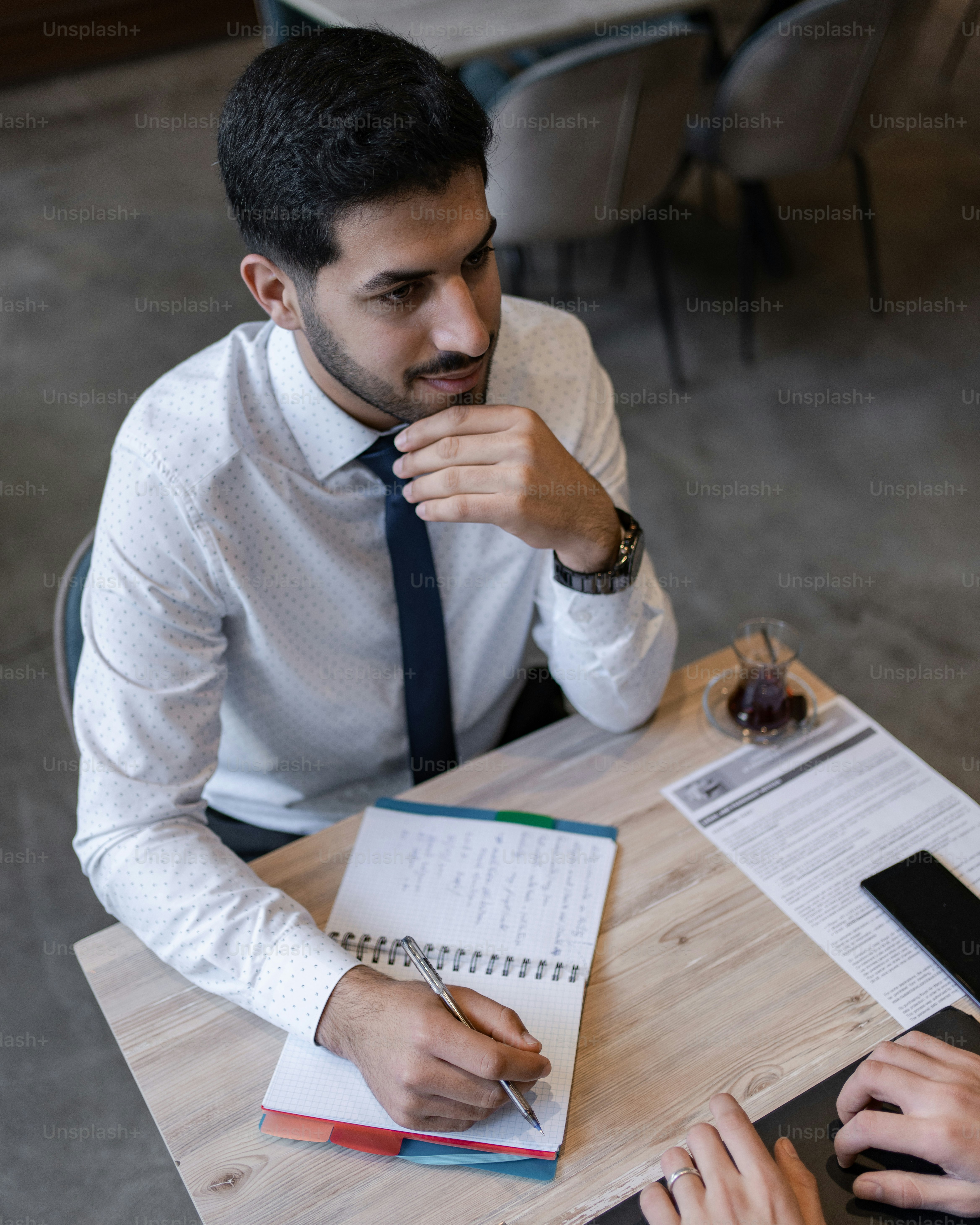 a man sitting at a table with a notebook and pen