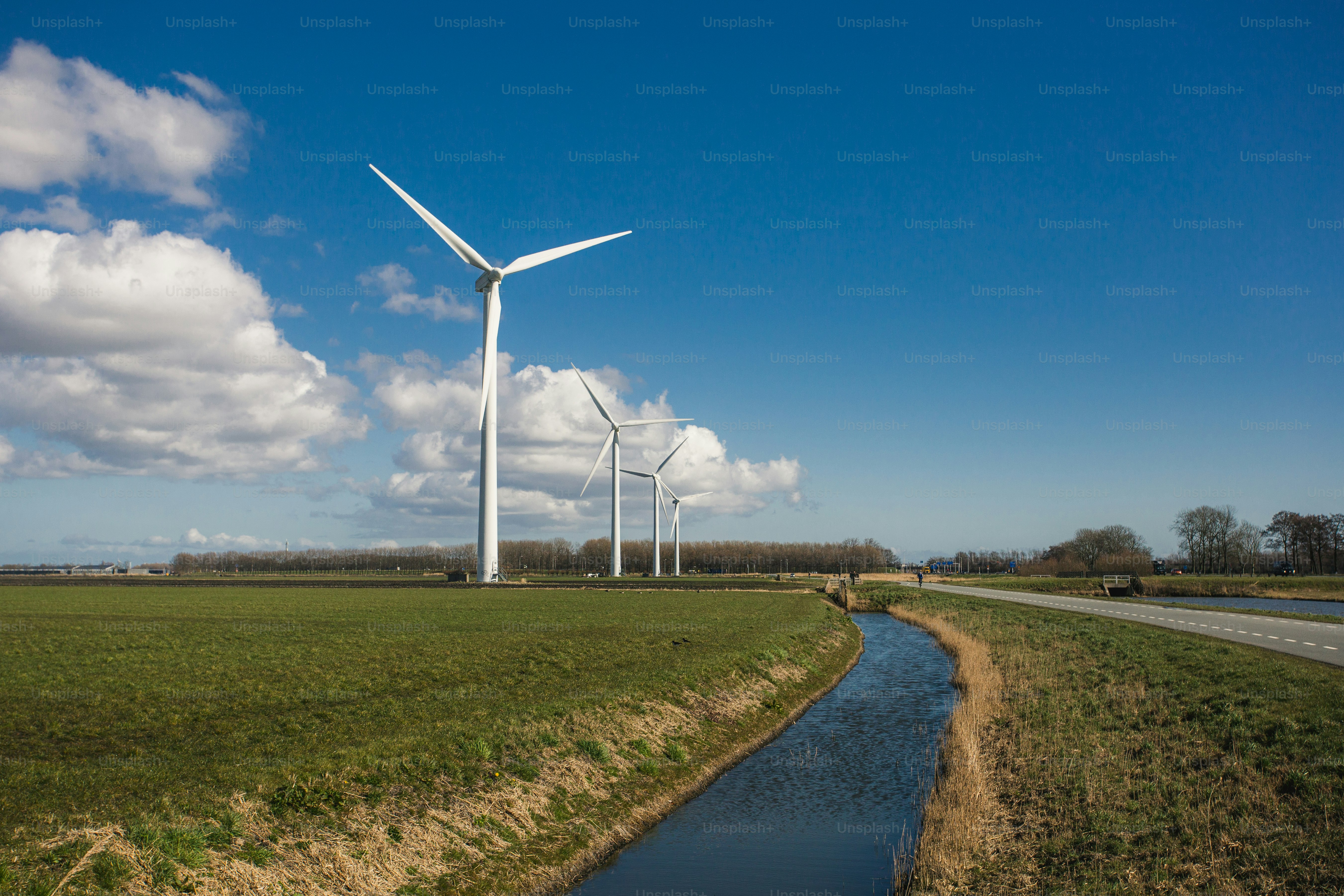 Un río que atraviesa un exuberante campo verde junto a turbinas eólicas