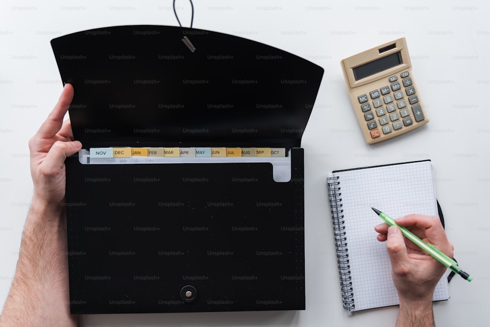 uma pessoa segurando uma caneta e um caderno com uma calculadora