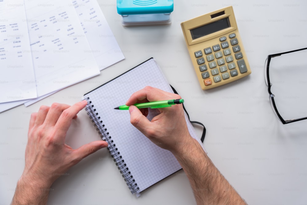 a person writing on a notebook with a green pen