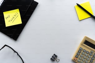 uma mesa com calculadora, caneta, óculos e uma nota
