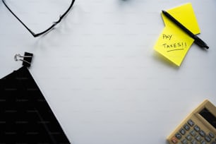 Una nota amarilla Post It sentada encima de un escritorio junto a un calcula