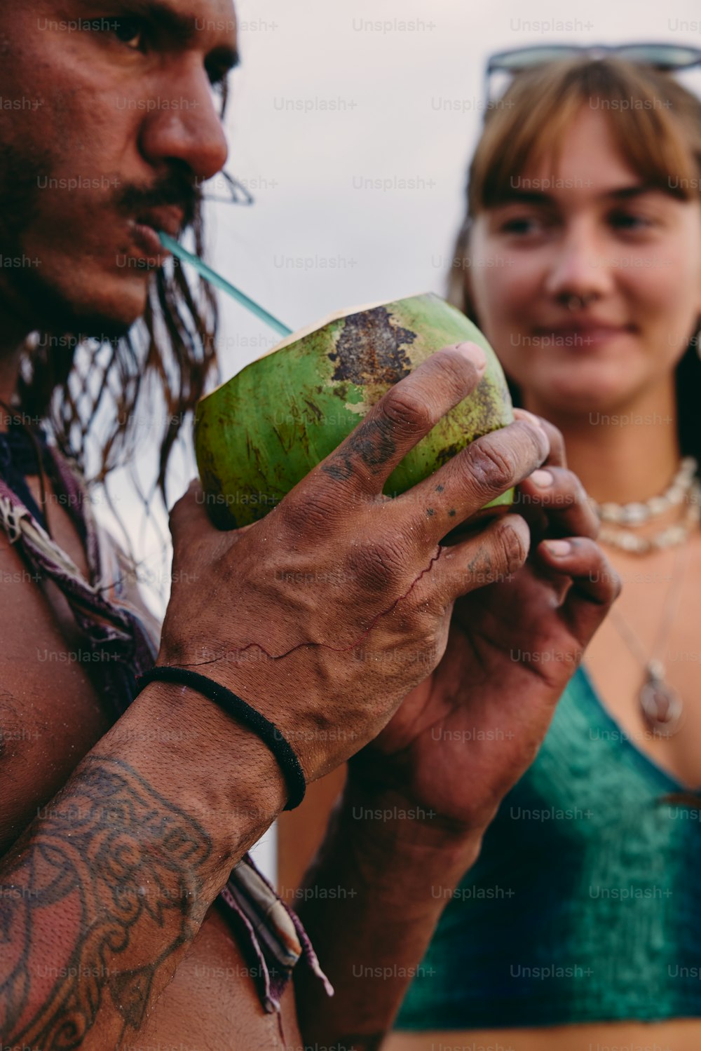 a man holding a green coconut next to a woman