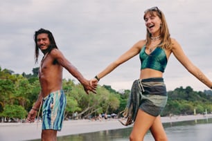 a man and a woman holding hands on a beach