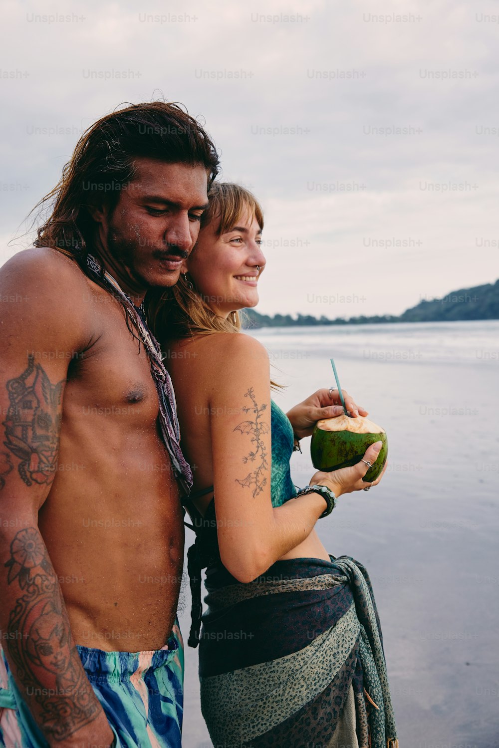 a man and woman standing next to each other on a beach