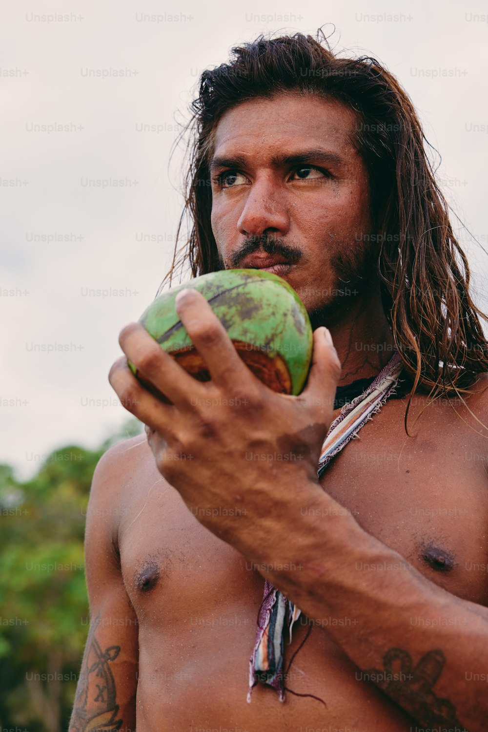 a man with long hair holding a coconut