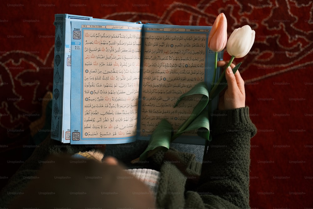 a person holding a book with a flower in it