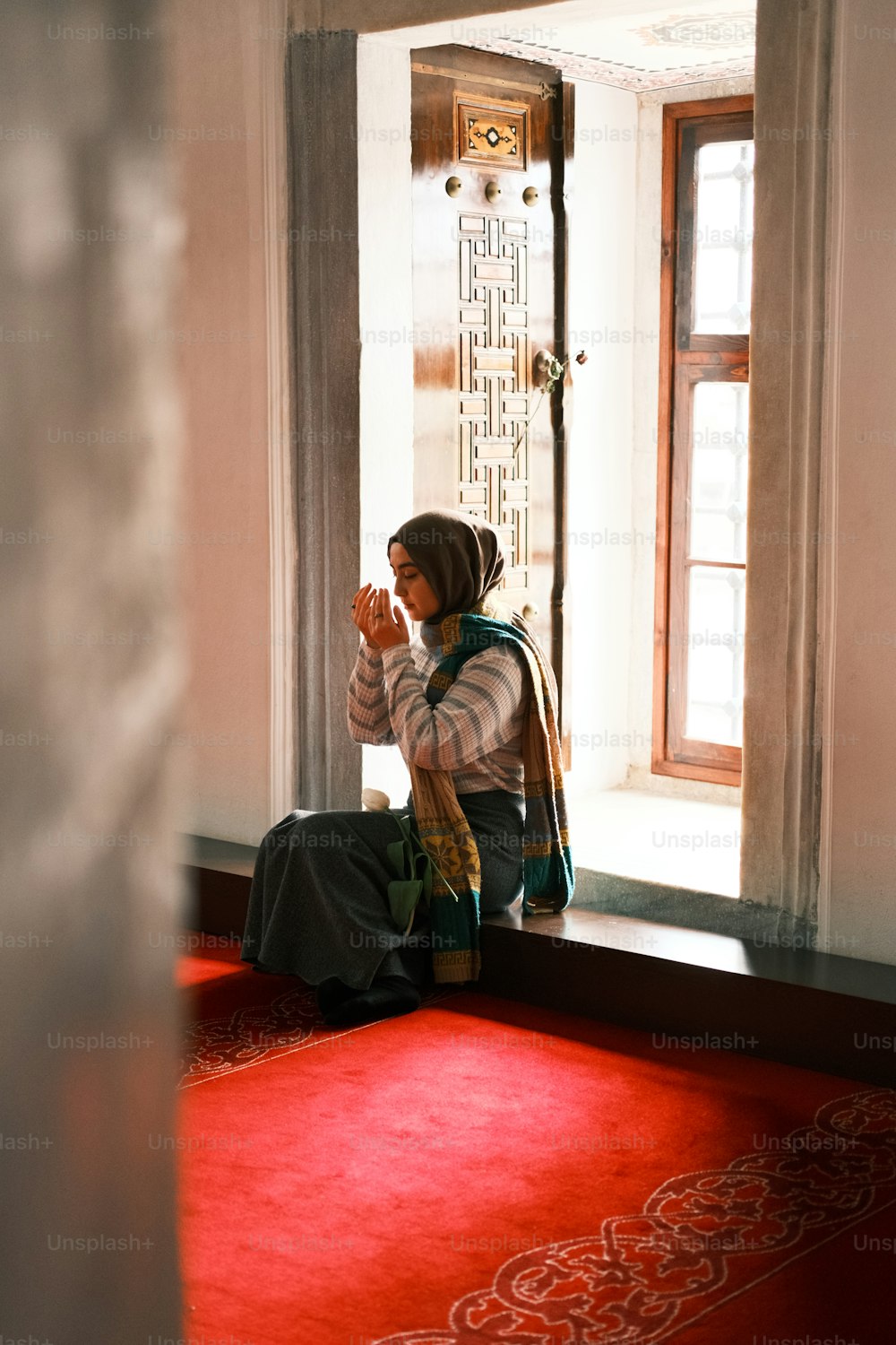 a woman sitting on a window sill praying