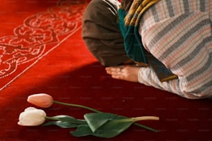 a person sitting on the floor with a flower on the floor