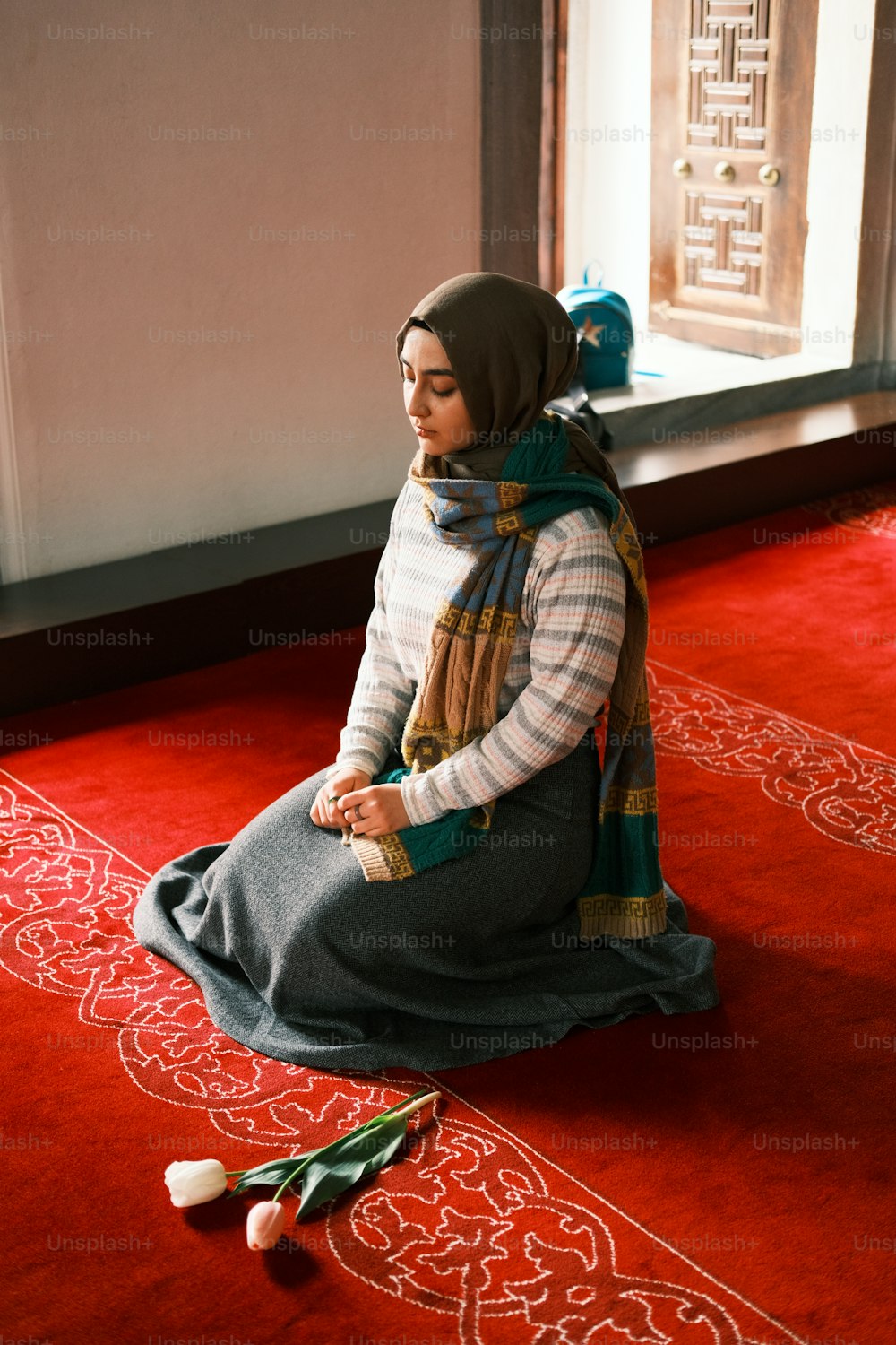 une femme assise par terre devant une fenêtre