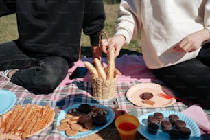 two people sitting at a picnic table with snacks