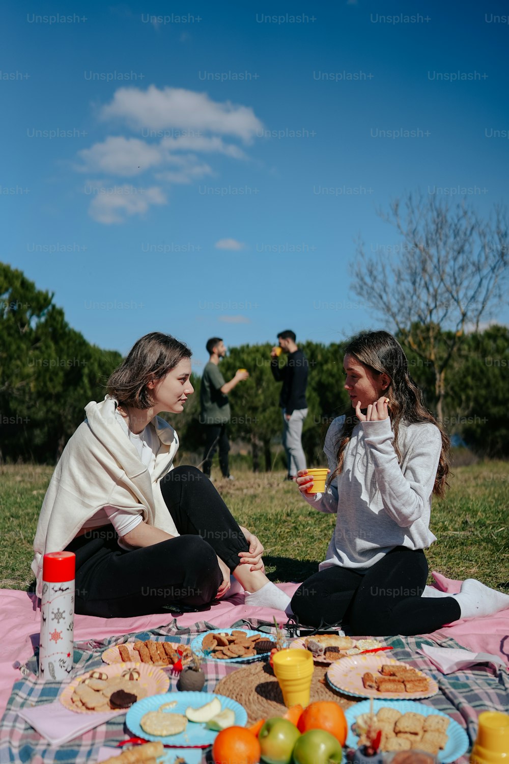 a couple of women sitting on top of a blanket
