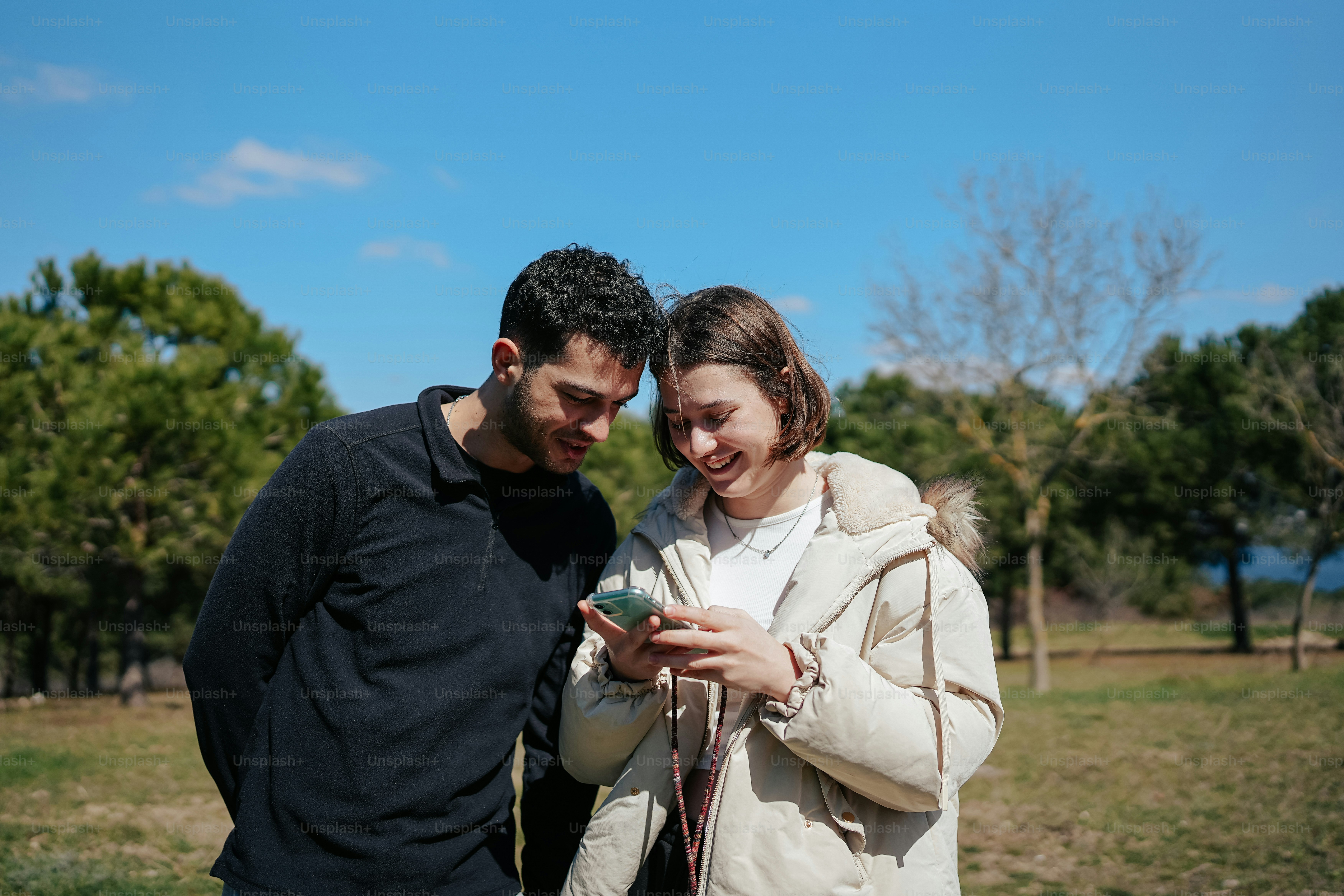 a man standing next to a woman holding a cell phone
