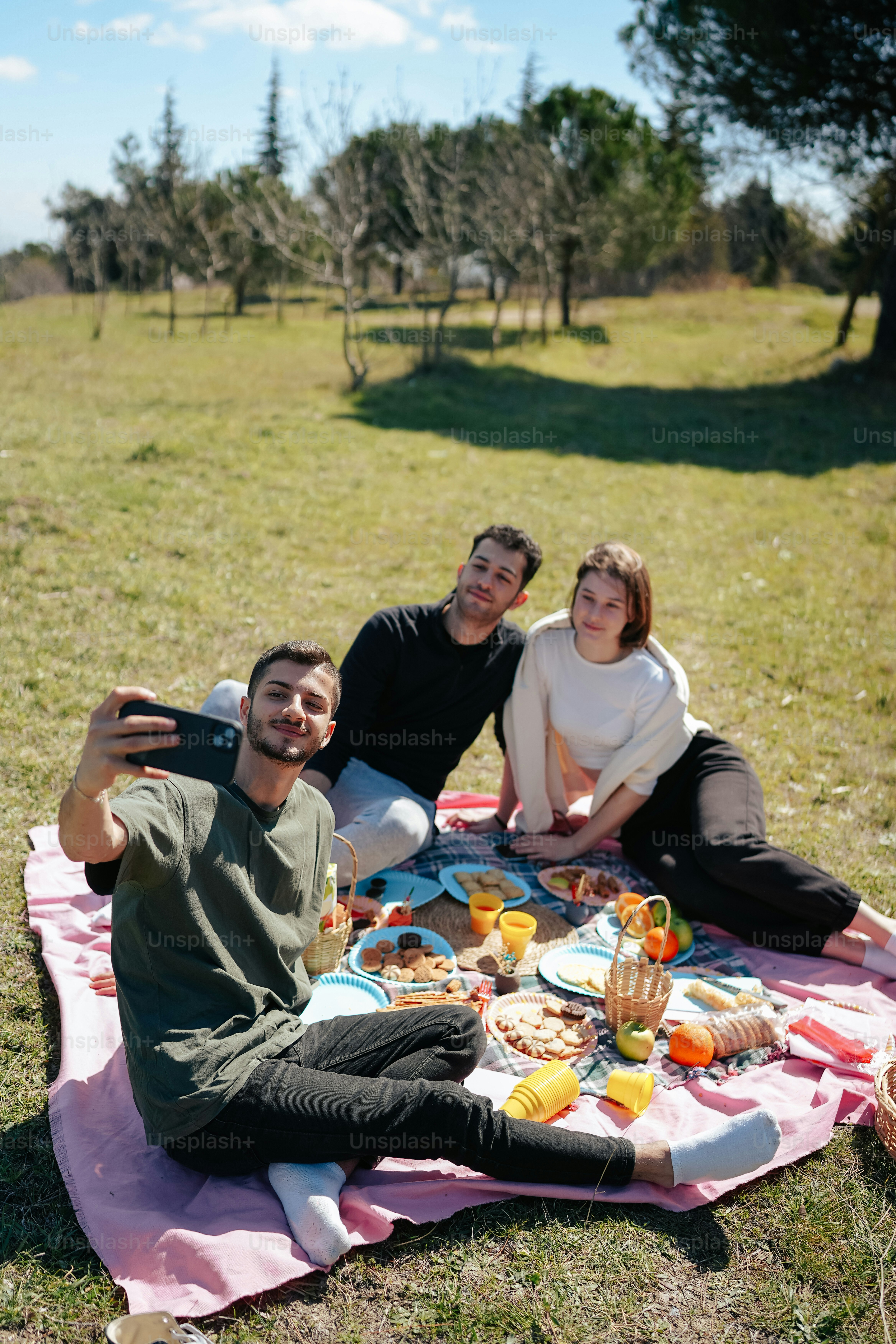 a group of people sitting on a blanket in a field