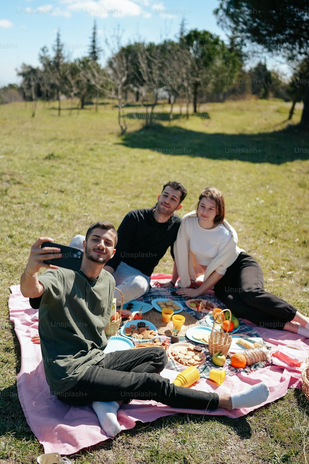 a group of people sitting on a blanket in a field