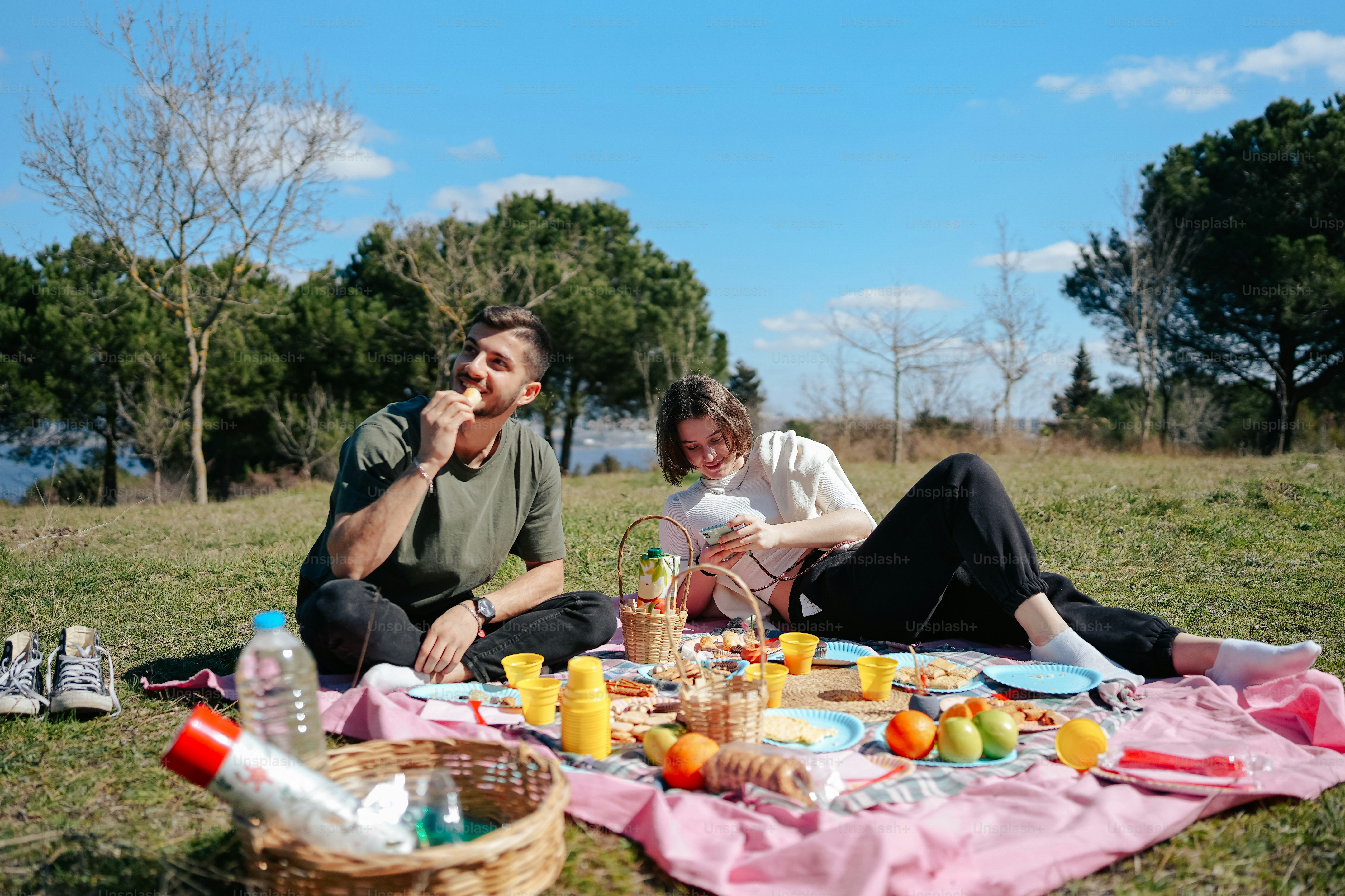 a man and a woman sitting on a blanket in the grass
