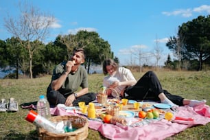 a man and a woman sitting on a blanket in the grass