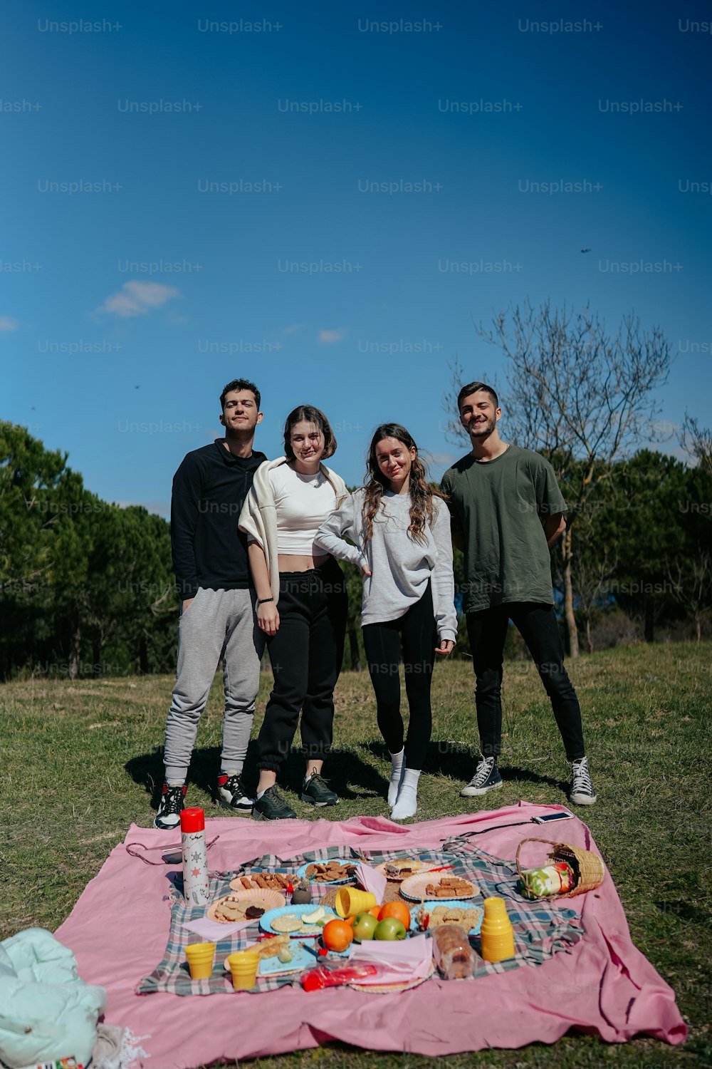 a group of people standing around a picnic blanket