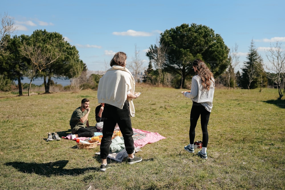 a group of people sitting on top of a grass covered field