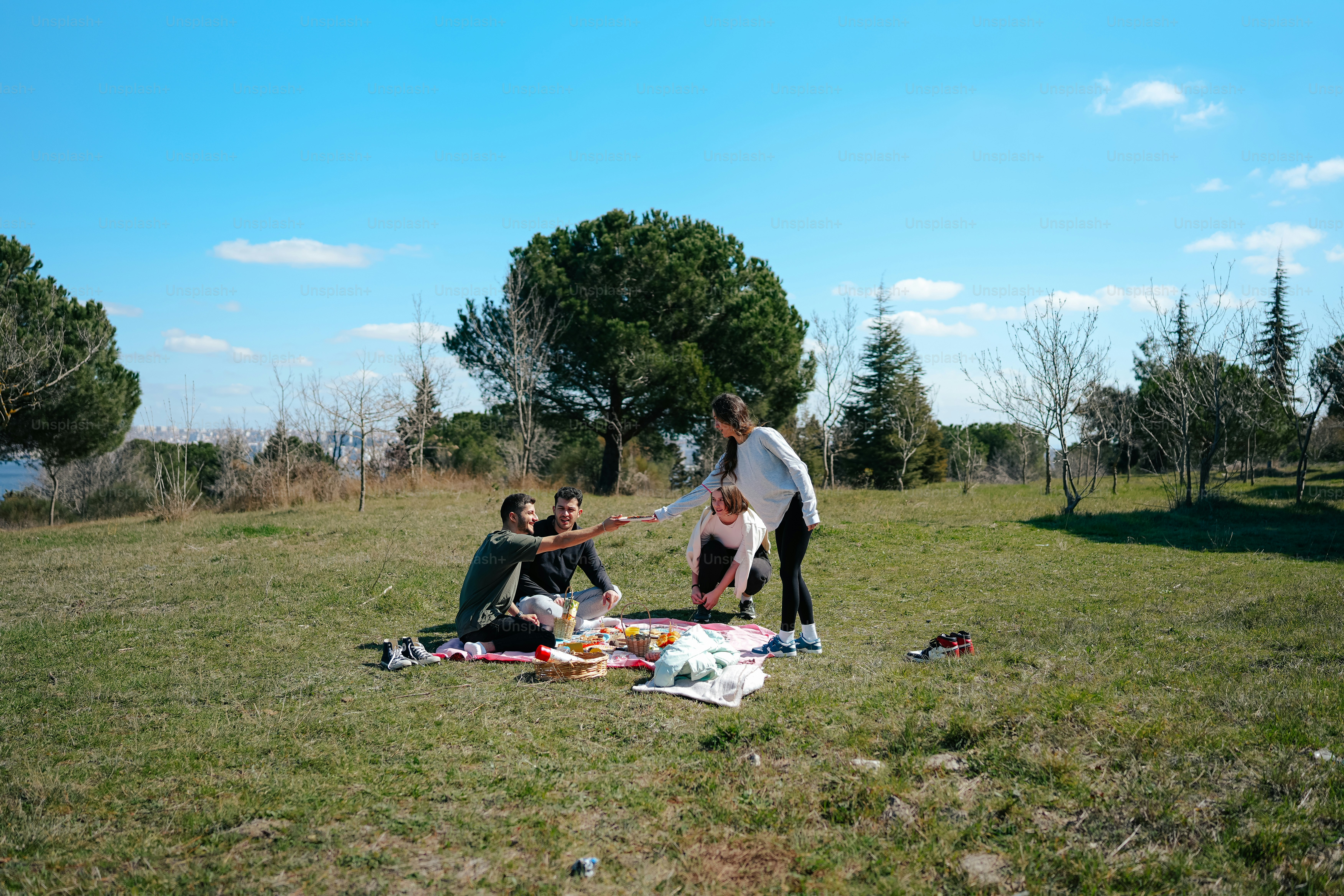 a group of people sitting on top of a grass covered field