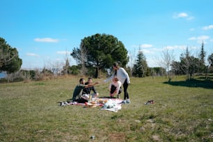 a group of people sitting on top of a grass covered field