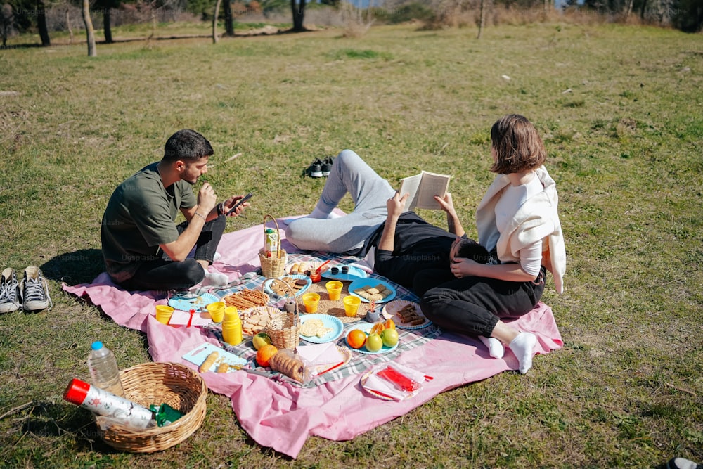 a man and a woman sitting on a blanket in a field